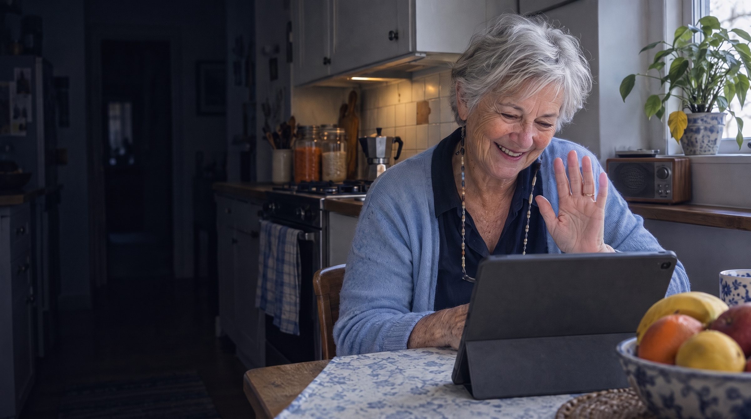 An older woman laughing on a video call in her kitchen